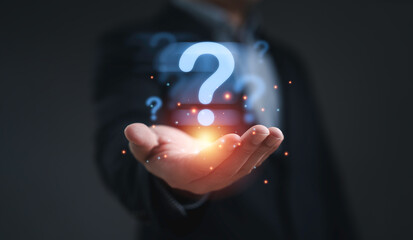 Businessman holding glowing question mark symbol representing problem solving uncertainty curiosity...