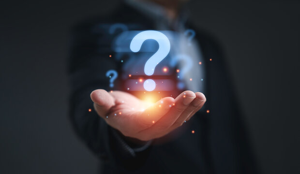 Businessman holding glowing question mark symbol representing problem solving uncertainty curiosity innovation decision making challenge and creative thinking concept in business and technology.