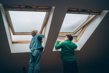 Father and son working together to open skylights in a cozy home on a rainy day