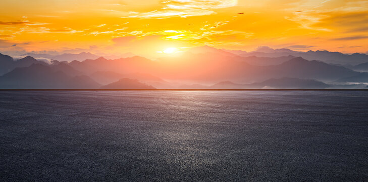 Empty asphalt road and beautiful mountain range with dramatic sky clouds at sunset