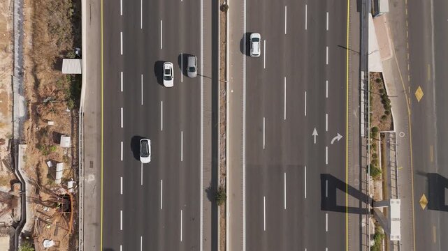 Aerial view of Highway road 6 displaying the grey asphalt texture contrasting with the white lane markers, Rosh HaAyin, North District, Israel.