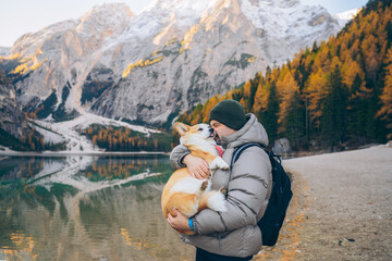 Man enjoy a moment together by the lake in the mountains with their corgi on a sunny day