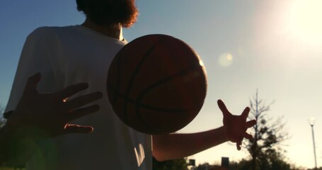 Slow motion  close up of young man playing practice basketball on outdoor court at sunset. Natural light, urban sport lifestyle and freedom concept. - Powered by Adobe