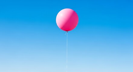 Pink balloon floating in the bright blue sky on a sunny day