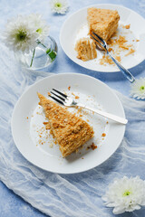 Napoleon cake dessert layers of puff pastry and cream filling on plates with forks and white flowers