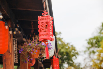 Naklejka premium Red lanterns hang from an outdoor wooden porch with potted flowers