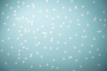White heart shape confetti on a light blue background.