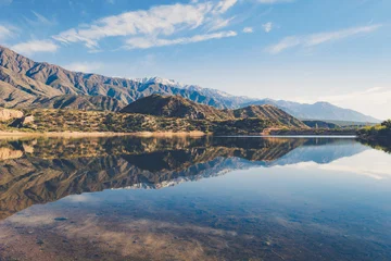 Poster Reflectie Natural landscape of mountains perfectly reflected in a crystal-clear lake under a clear sky. The scene conveys calm and purity, with the golden tones of the sun highlighting the textures of the moun  © josho photographer