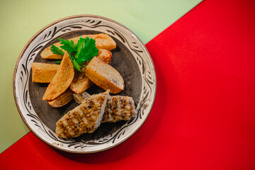 Grilled chicken and potato wedges on decorative plate with parsley garnish
