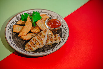Grilled chicken with potato wedges and ketchup on artistic plate
