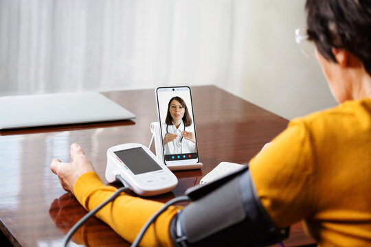 Video call with doctor telemedicine concept. Senior woman measuring her blood pressure. Retired uses medicine digital device tonometer for control health at home.