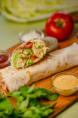 Grilled chicken wrap with fresh vegetables on wooden board