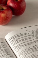 Fruit of the spirit inspirational biblical text in open holy bible book with red apples. Christian spiritual growth, love, joy, peace, and obedience to God Jesus Christ concept.