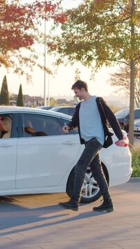 Happy and excited young man jumping up with joy from long-awaited news. Boy dancing in good mood with hands raised up and getting into the car happily.Happiness. Joy.Good mood.Dance