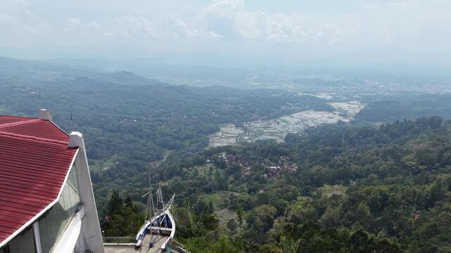 Aerial view of rice fields and terraces surrounded by tropical hills and traditional houses in Tana Toraja, Indonesia.	