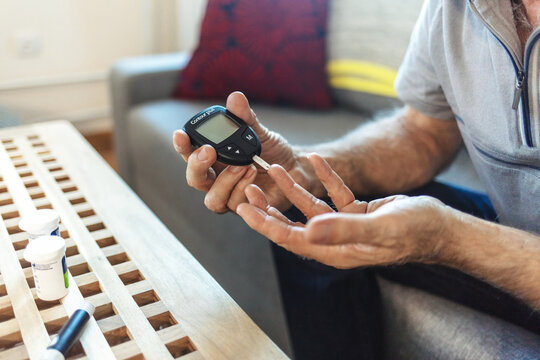Finger, healthcare and diabetes with a senior man testing his blood sugar level while in his retirement home. Medical, wellness and test with a mature male using a glucometer to measure his glucose.