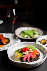 A gourmet meal featuring a vibrant salad with raw salmon and tuna, quinoa, and vegetables, with a...