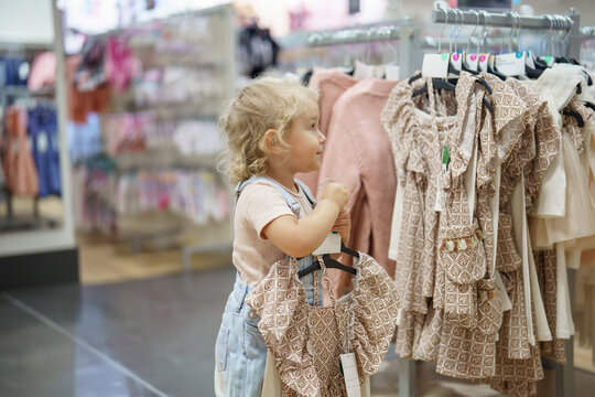 Little shopper explores fashion in Children's Department at Macy's, considering a dress