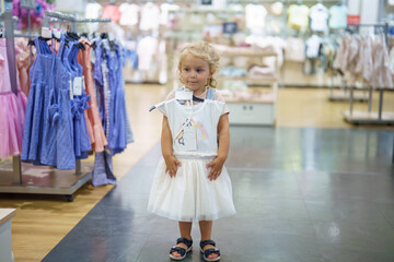 Little girl dreams of unicorns in a bright and cheerful children's clothing store