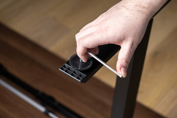 Skilled hand precisely using an Allen wrench to securely fasten a black furniture leg, illustrating efficient home assembly, DIY projects, and practical maintenance solutions