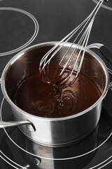Mixing melted chocolate with whisk in pot, closeup