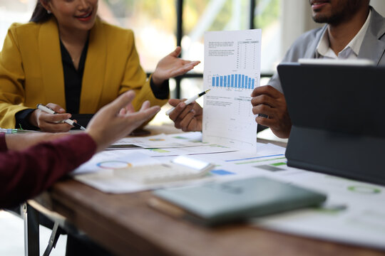 Businessman are examining financial charts and graphs during a meeting at their office desk, teamwork and collaboration in analyzing business performance.