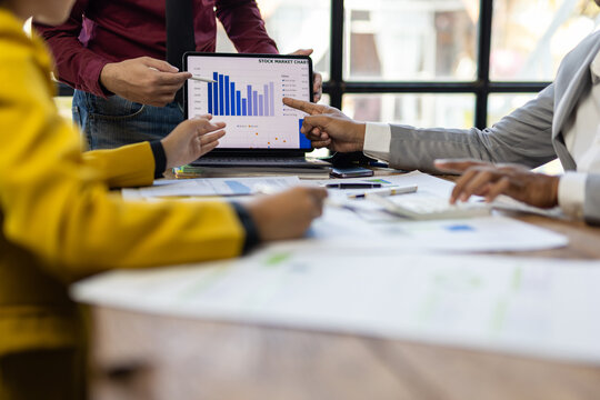 Business people analyzing financial chart on tablet during corporate meeting.