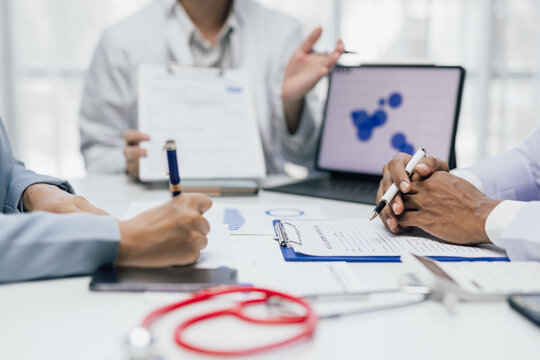 Doctors and healthcare administrator analyzing medical data and costs during meeting.