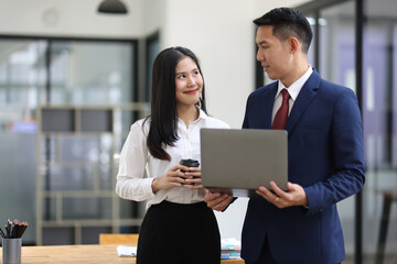 Asian businesspeople working together using laptop in office meeting room.