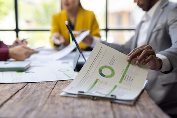 Business people analyzing financial documents with charts and graphs at office meeting. Business team reviewing financial reports and analyzing market data during a collaborative meeting.