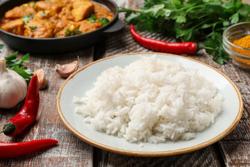 Cooked rice, chicken tikka masala and spices on wooden table, closeup