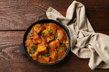 Chicken tikka masala with parsley on wooden table, top view