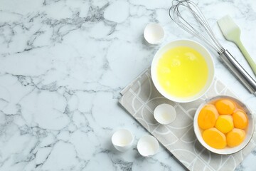 Egg whites, yolks, whisk and brush on white marble table, flat lay. Space for text