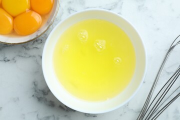 Egg whites, yolks and whisk on white marble table, flat lay