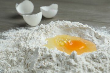 Broken eggs, yolk and flour on wooden table, closeup