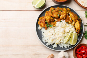 Delicious chicken tikka masala with rice, parsley, lime and spices on light wooden table, flat lay. Space for text