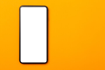Flat lay, top view of orange office table desk with smartphone blank screen mockup with clipping path. Modern working space.