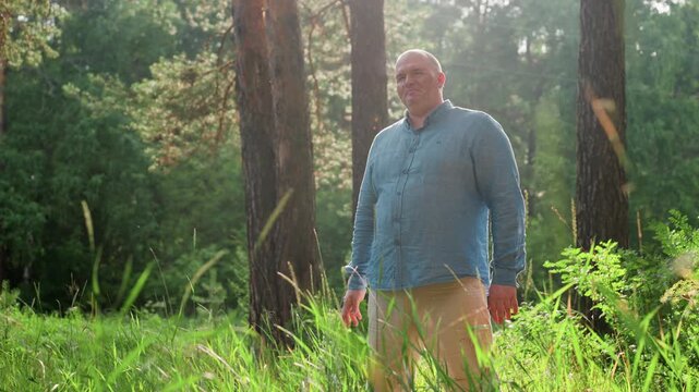 Male figure standing quietly in green forest swinging arms thoughtfully under warm sunlight, surrounded by tall trees and lush grass, reflecting peaceful mood and calm connection with nature