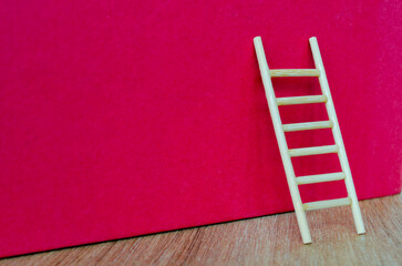 Side view of small ladder on dark red cover background with customizable space for text.