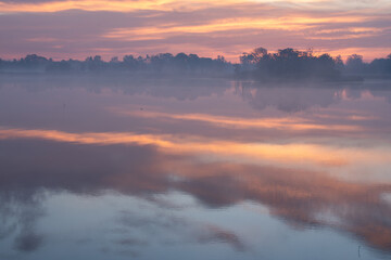 Fototapeta premium Jesienny wschó słońca we mgle, nad wodą. 