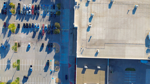 Open parking lot at large retail store shopping mall strip near Lewisville, Texas commercial mixed zone. ADA spaces, tree islands, and empty rooftop contrast consumer flow and infrastructure use