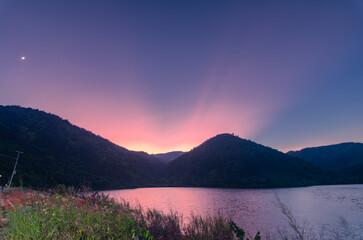 The beauty of the twilight rays over the reservoir and mountains in the countryside of Northern Thailand.