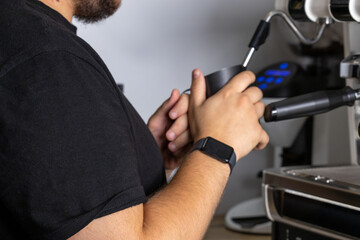 Obraz premium Close up of barista frothing milk with steam wand in modern cafe. Specialty beverage preparation concept with professional espresso equipment and warm lighting.