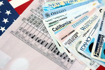 Big amount of driving licenses from different USA states on flag close up. Stack of driving license specimen cards