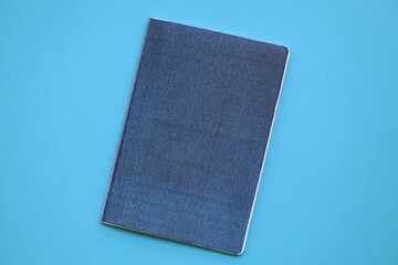 Generic passport book on light blue paper background close up. Travel document on blue surface