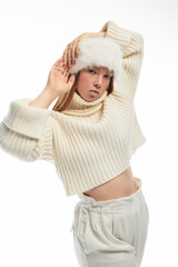 Young redhead woman showcases cozy winter fashion in plush fur hat and sweater