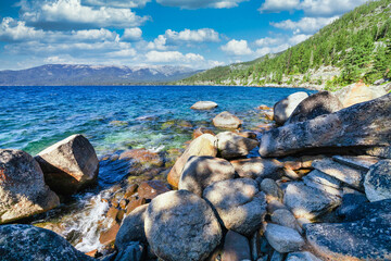 Lake Tahoe California USA view of clear turquoise water with granite rocks and pine forest along mountain shore under blue sky with clouds scenic summer landscape of Sierra Nevada nature