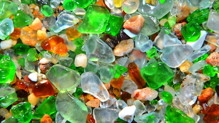 Colourful background of sea glass. Kelly green, aqua blue, amber and pebbles.