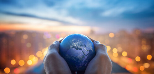Planet Earth in the hands of a man against the background of the lights of the evening city. Concept and symbol on the theme of ecology, religion. Elements of this image furnished by NASA.