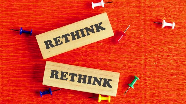 The conceptual word RETHINK appears on wooden blocks. The concept of views on events